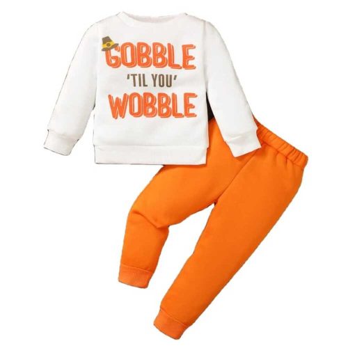 Boy wearing white “Gobble ‘Til You Wobble” sweatshirt and orange joggers