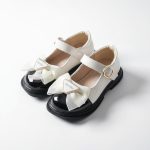 Girl’s glossy white Mary Jane shoes with black toe cap and satin bow