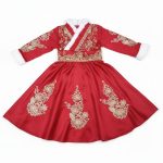 Girl wearing red satin dress with gold embroidery and white faux fur